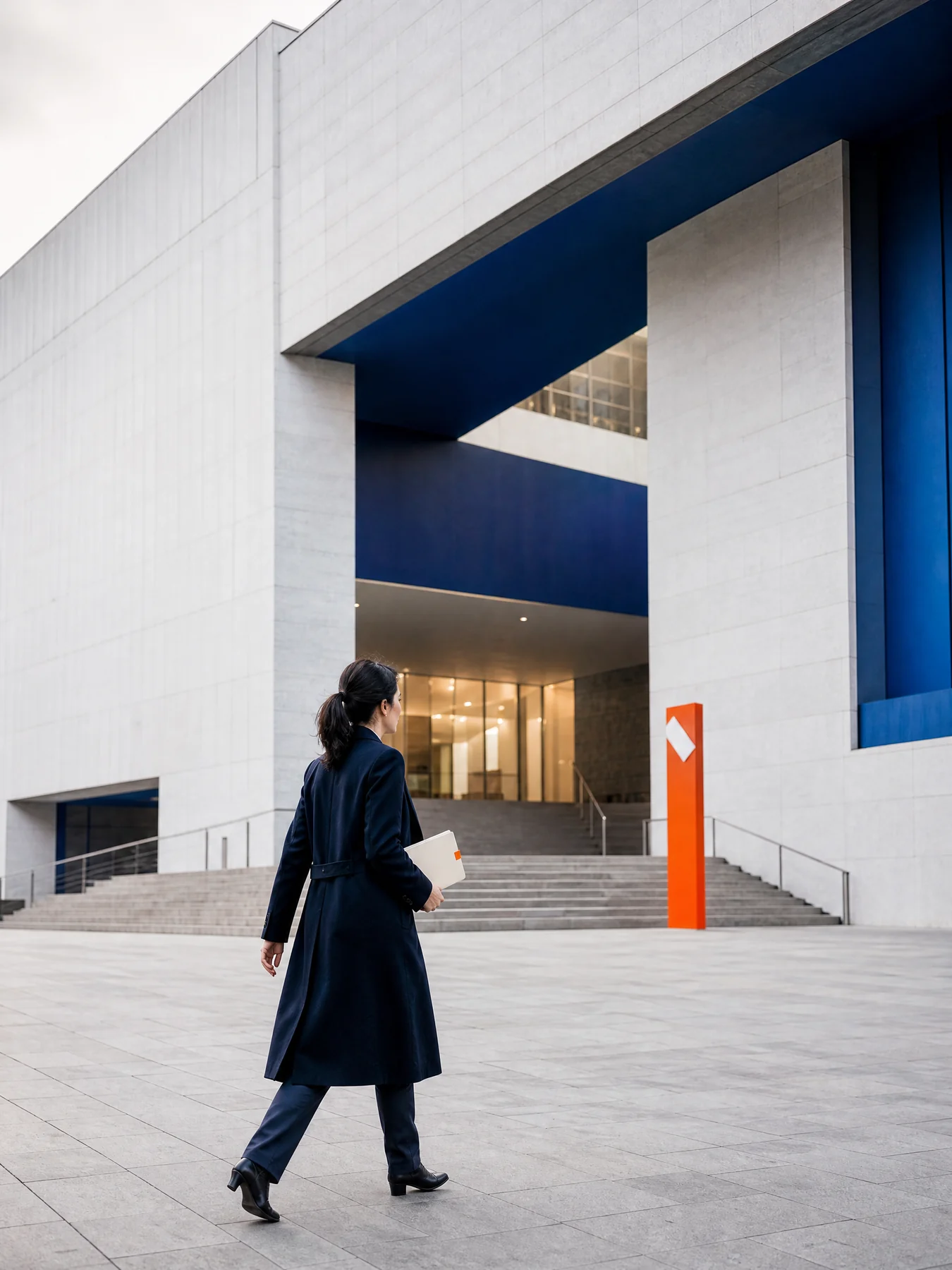 Professional crossing a civic plaza toward a modern building
